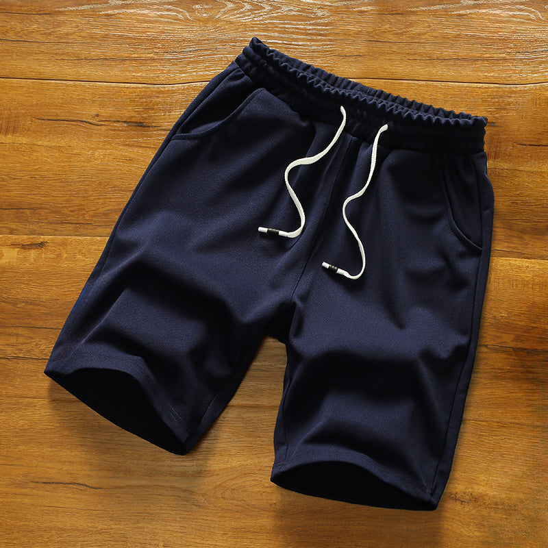 Modell som bär avslappnade, färgglada herrshorts med elastisk midja, perfekt för stranden eller sommarstilen.