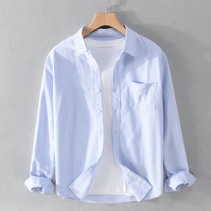 Blå herrskjorta långärmad med bröstficka, tidlös design, idealisk för både casual och formell stil