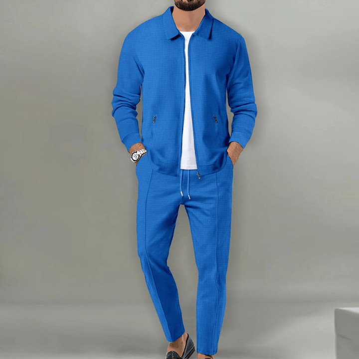 Man bär modern herrträningsjacka och byxor, demonstrerar avslappnad och sportig stil