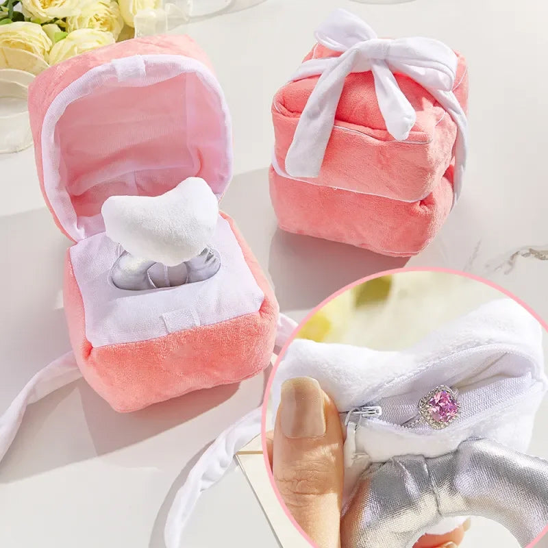 "Hjärtformad ringask i rosa plysch med dold dragkedja, perfekt för frieri och speciella tillfällen. Dekorativ och praktisk."