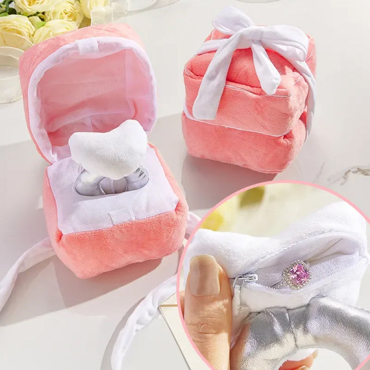 "Hjärtformad ringask i rosa plysch med dold dragkedja, perfekt för frieri och speciella tillfällen. Dekorativ och praktisk."