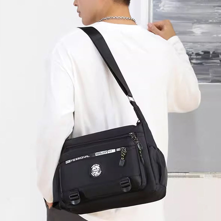 "Högkvalitativ svart axelväska för män med flera fickor, justerbara remmar och vattentät yta, sedd bakifrån."