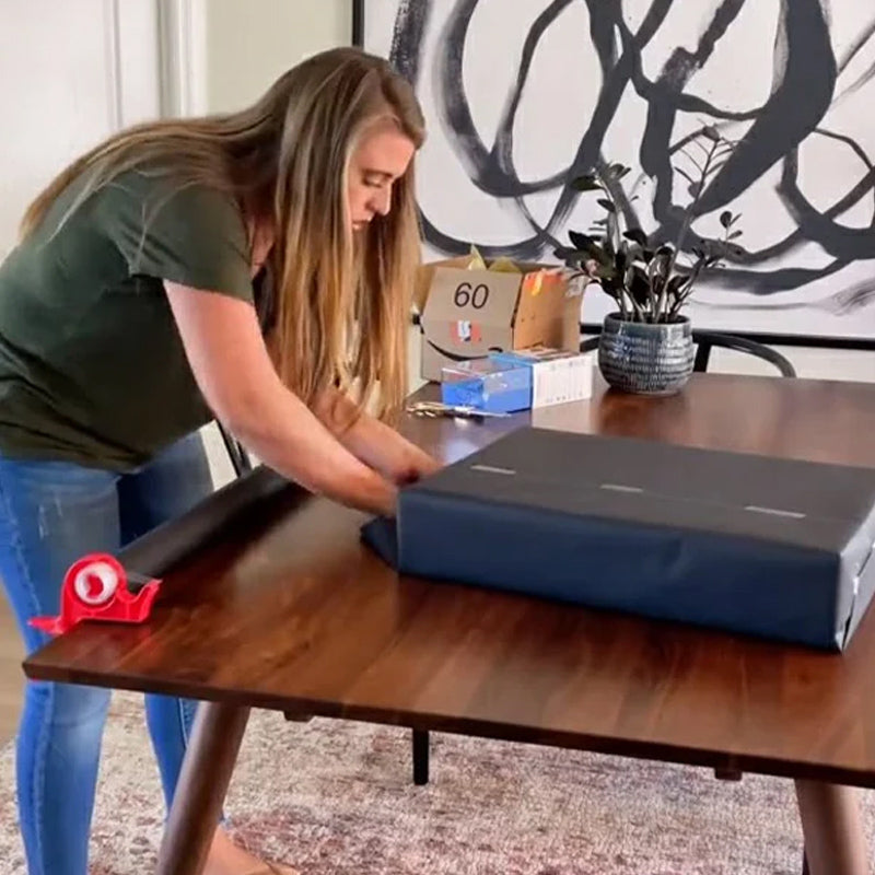 "Inslagningverktyg i röd och grå plast för presentinpackning, justerbar för olika pappersstorlekar."