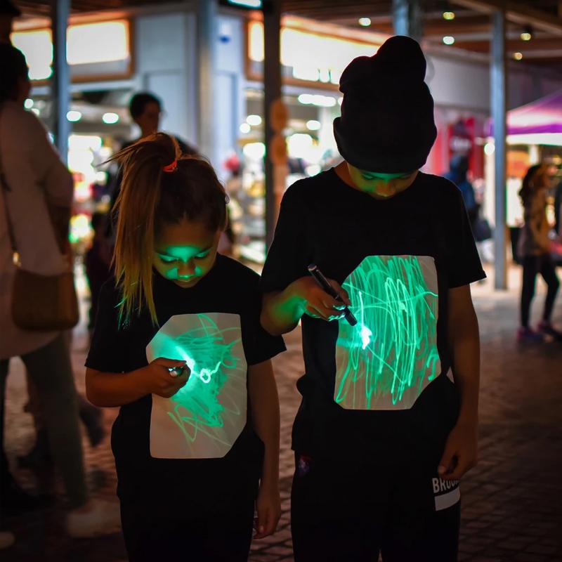"Interaktiv glödande unisex T-shirt med kreativa mönster, perfekt för mörka miljöer, inkluderar unik glödpenna."