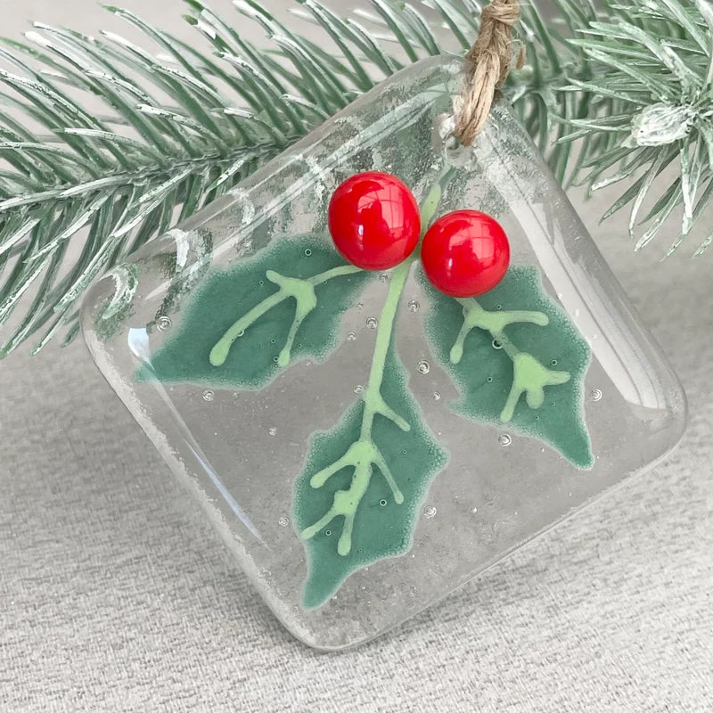 "Julgransdekoration i glas med detaljerade mönster, reflekterar ljus vackert, passar för festlig julstämning."