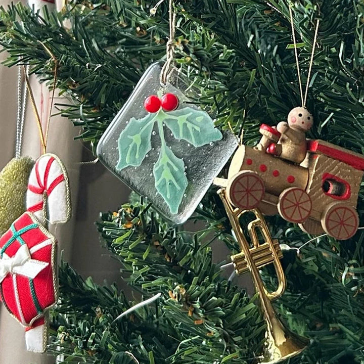 "Julgransdekoration i glas med detaljerade mönster, reflekterar ljus vackert, passar för festlig julstämning."