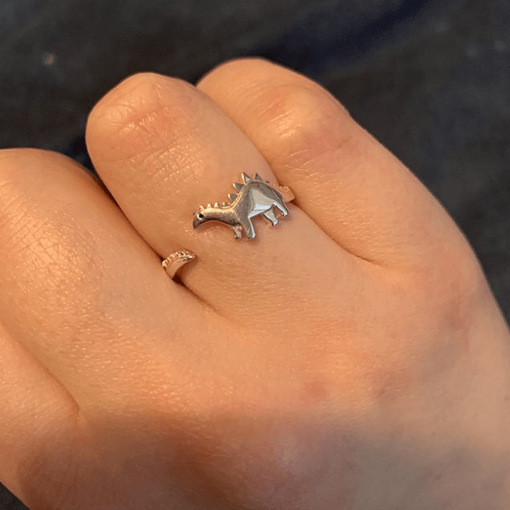 "Justerbar dinosauriering i silver med dinosauriemotiv; elegant, lekfull och perfekt för dinosaurieälskare."
