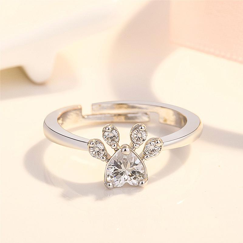 "Justerbar kattfotavtrycksring med zirkon, roséguld och vitt, elegant smycke för kattälskare."