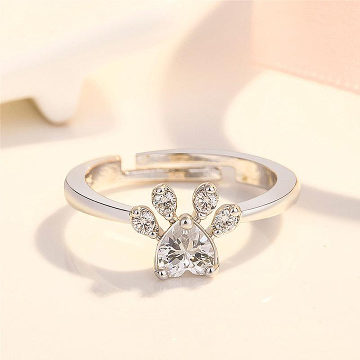 "Justerbar kattfotavtrycksring med zirkon, roséguld och vitt, elegant smycke för kattälskare."