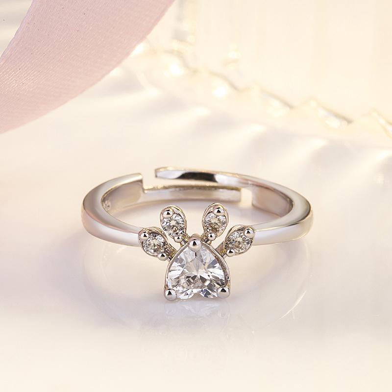 "Justerbar kattfotavtrycksring med zirkon, roséguld och vitt, elegant smycke för kattälskare."