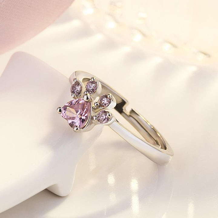 "Justerbar kattfotavtrycksring med zirkon, roséguld och vitt, elegant smycke för kattälskare."