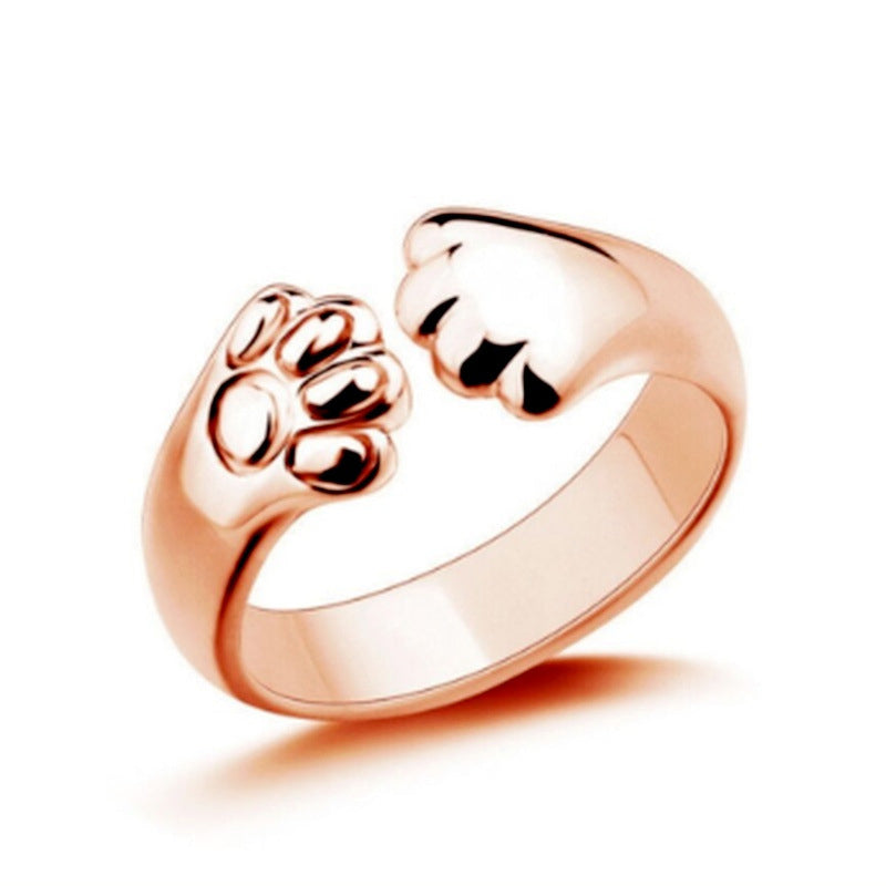 "Justerbar ring med hund- och katt-tassmotiv i guld, roséguld, silver och svart för djurälskare, unik smyckesdesign."