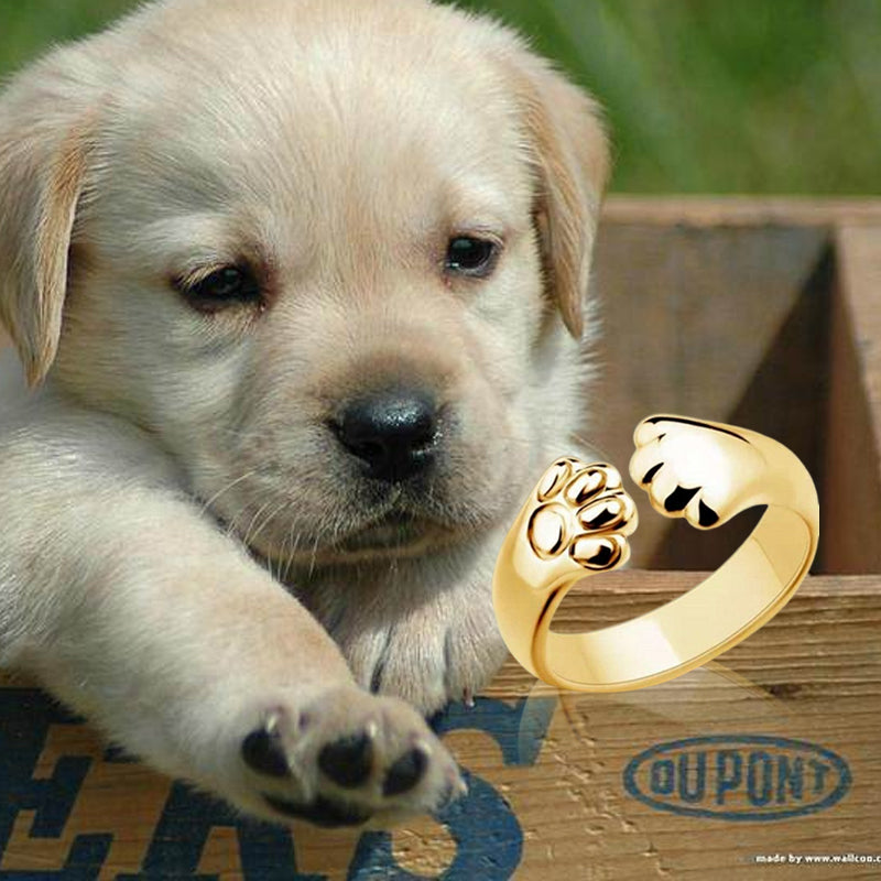 "Justerbar ring med hund- och katt-tassmotiv i guld, roséguld, silver och svart för djurälskare, unik smyckesdesign."