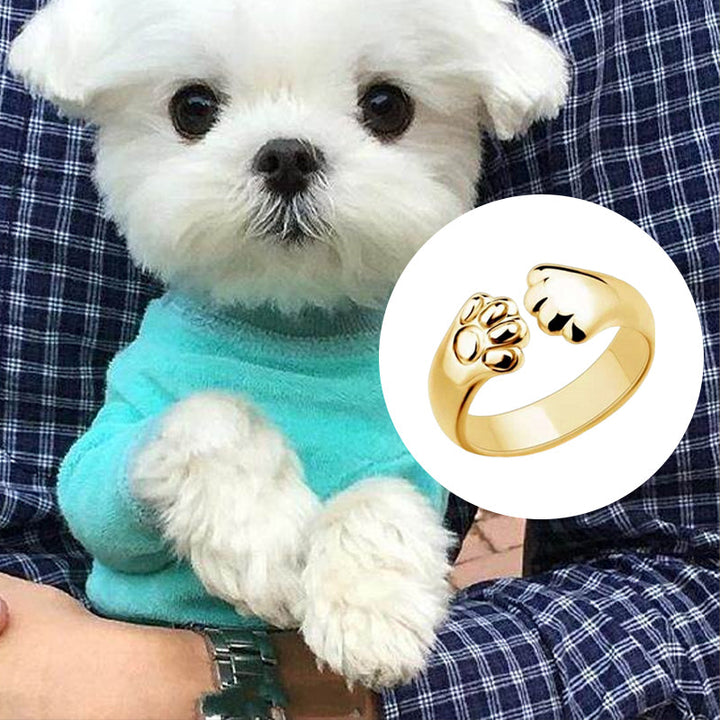 "Justerbar ring med hund- och katt-tassmotiv i guld, roséguld, silver och svart för djurälskare, unik smyckesdesign."