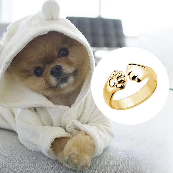 "Justerbar ring med hund- och katt-tassmotiv i guld, roséguld, silver och svart för djurälskare, unik smyckesdesign."