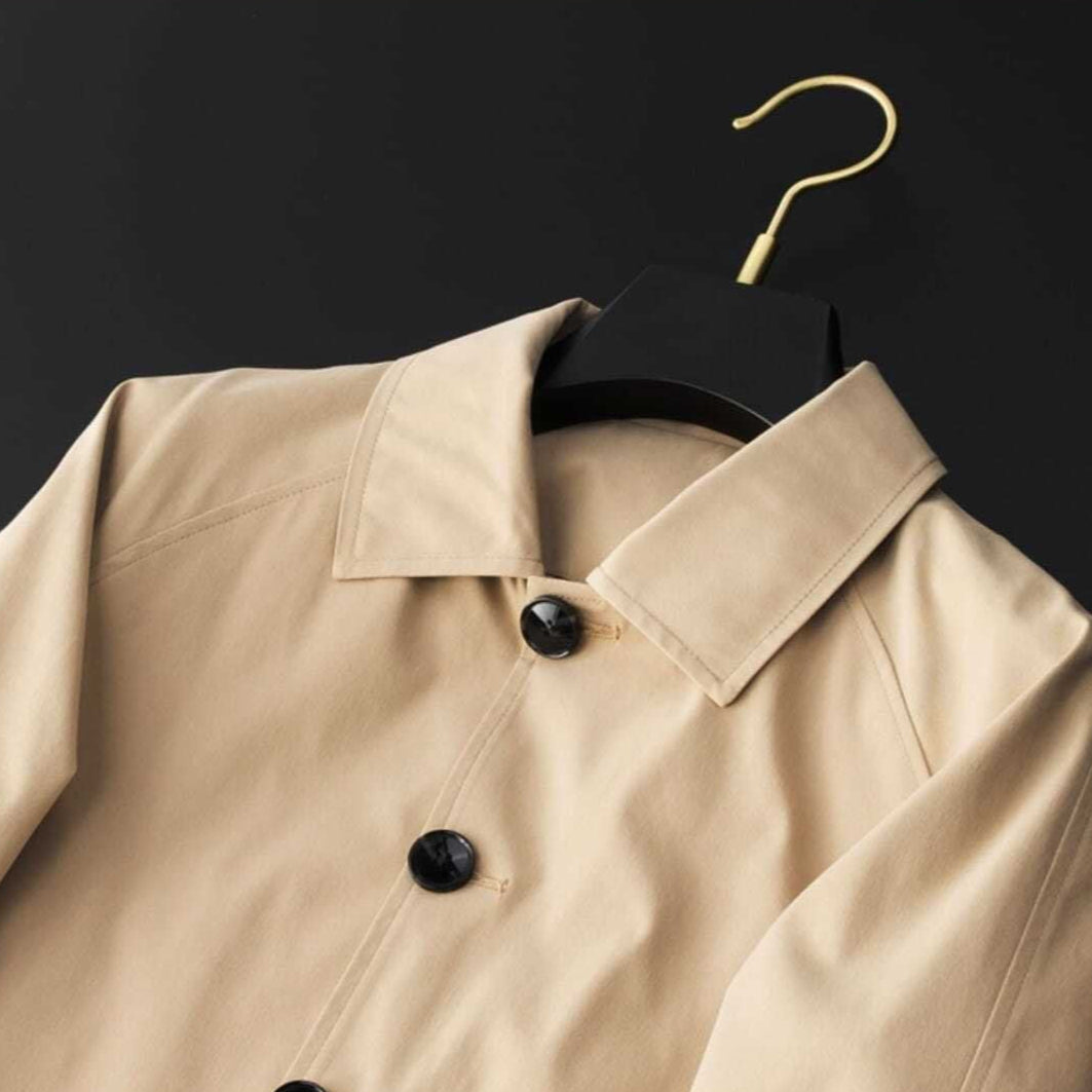 Stilren kort damtrenchcoat med krage i neutral färg, mångsidigt ytterplagg för våren och hösten.