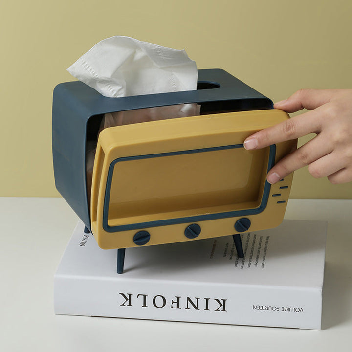 "Kreativ retro TV-servettlåda med mobilhållare i pastellfärger, nostalgi design för smart och stilren inredning."
