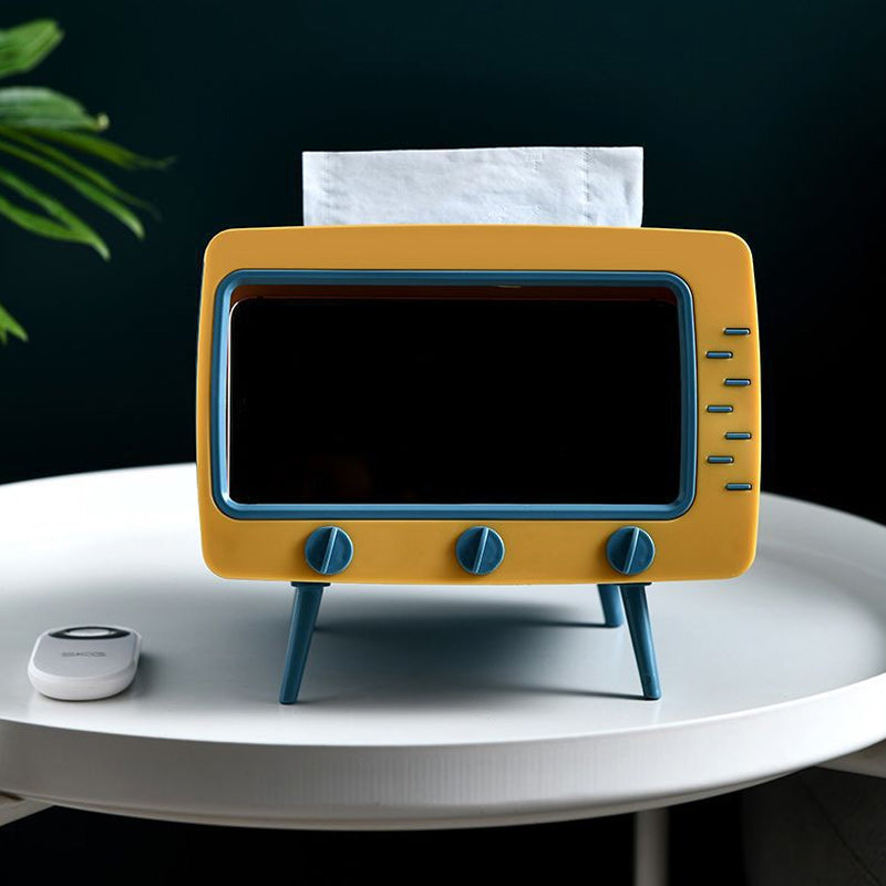 "Kreativ retro TV-servettlåda med mobilhållare i pastellfärger, nostalgi design för smart och stilren inredning."