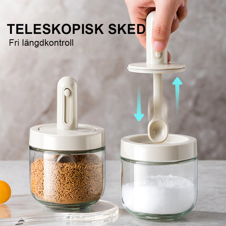 Kryddburk i glas med grönt och vitt skedlock, justerbart för enkel dosering, elegant design för köksanvändning.