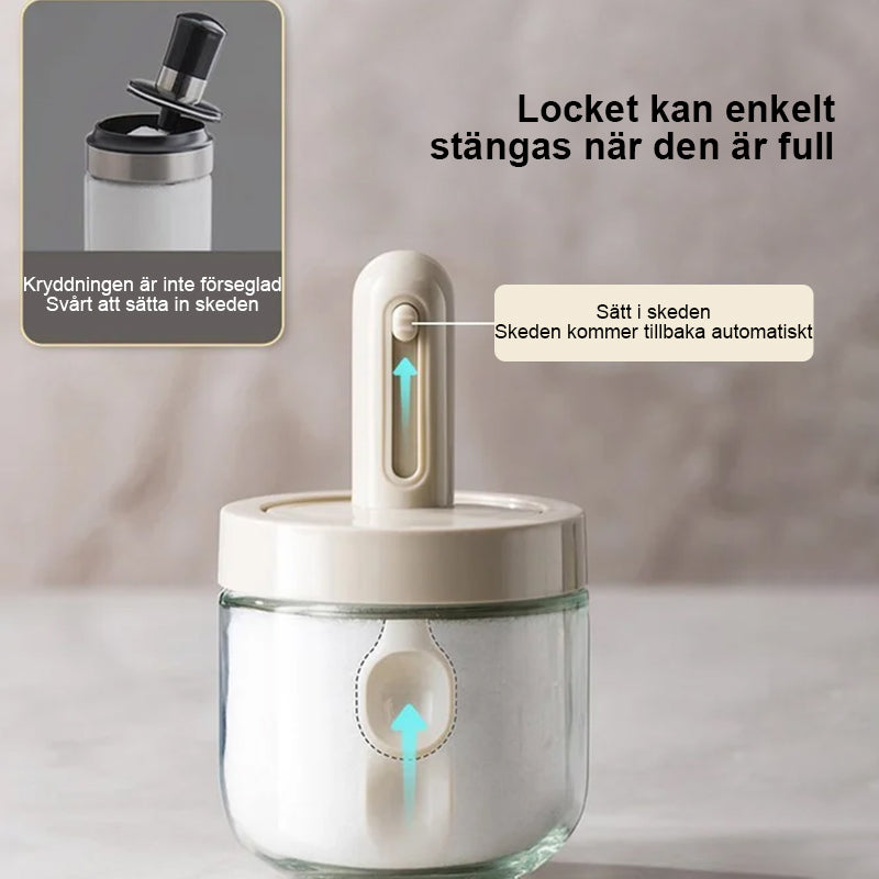 Kryddburk i glas med grönt och vitt skedlock, justerbart för enkel dosering, elegant design för köksanvändning.