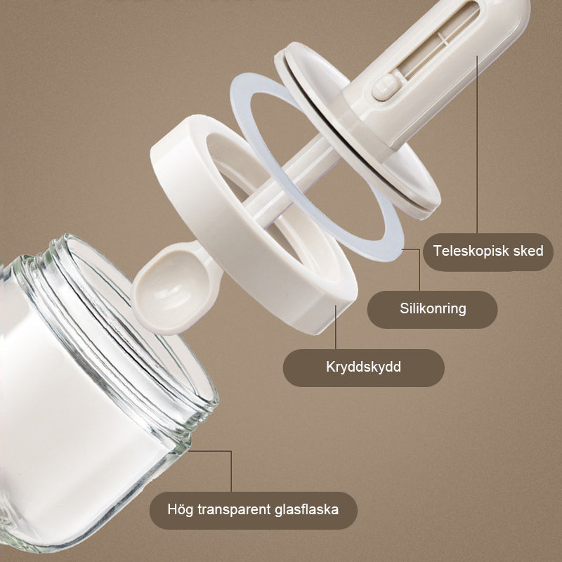 Kryddburk i glas med grönt och vitt skedlock, justerbart för enkel dosering, elegant design för köksanvändning.