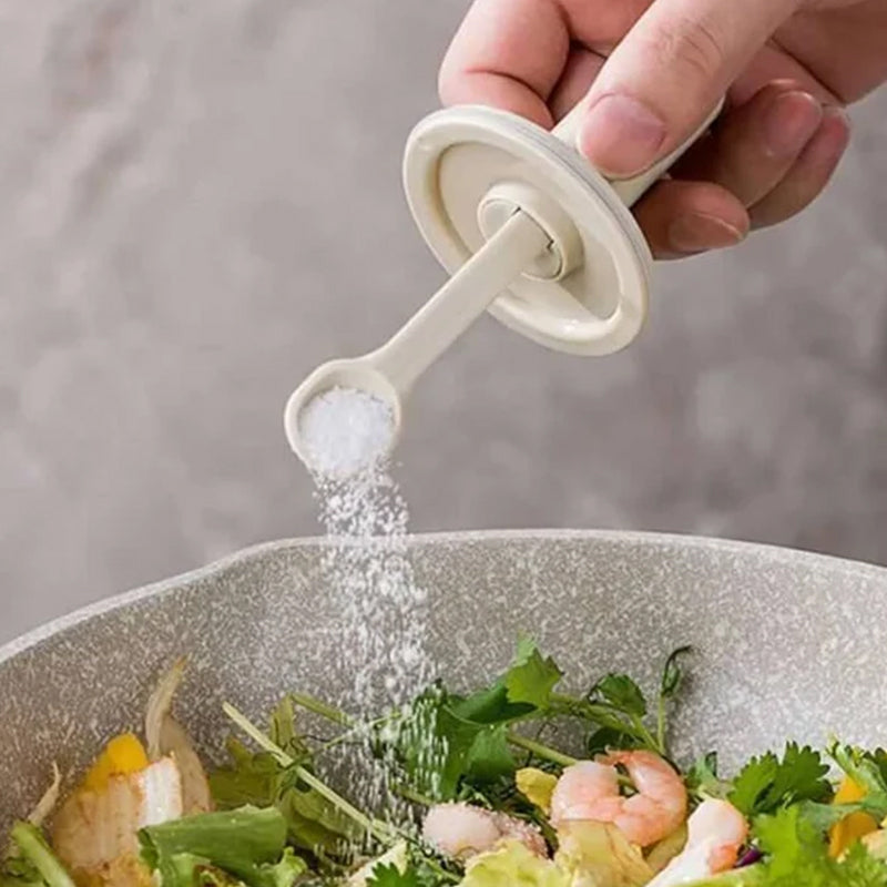 Kryddburk i glas med grönt och vitt skedlock, justerbart för enkel dosering, elegant design för köksanvändning.