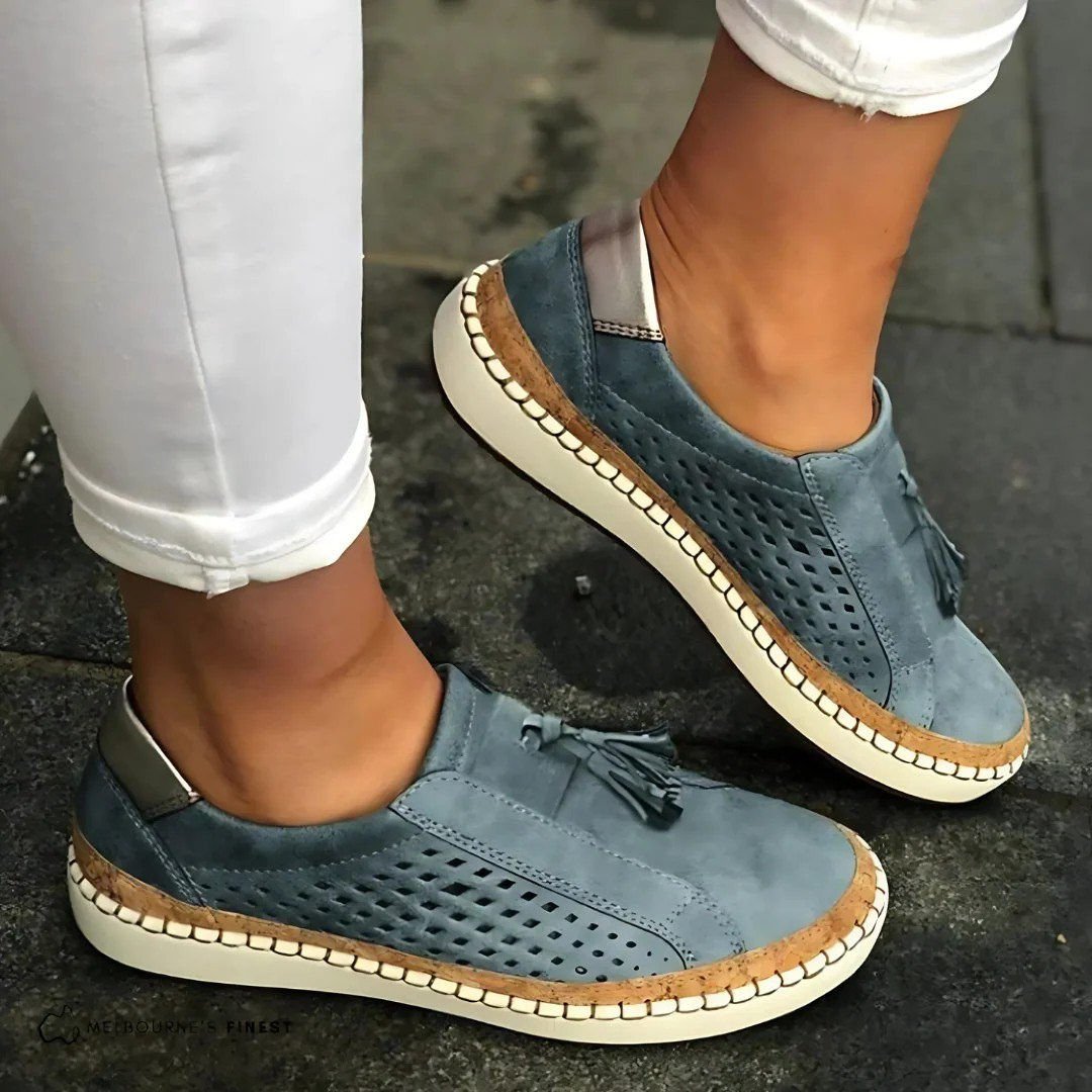 Ett par vita slip-on sneakers för kvinnor, från sidan, framhäver den bekväma designen för vardagsbruk.