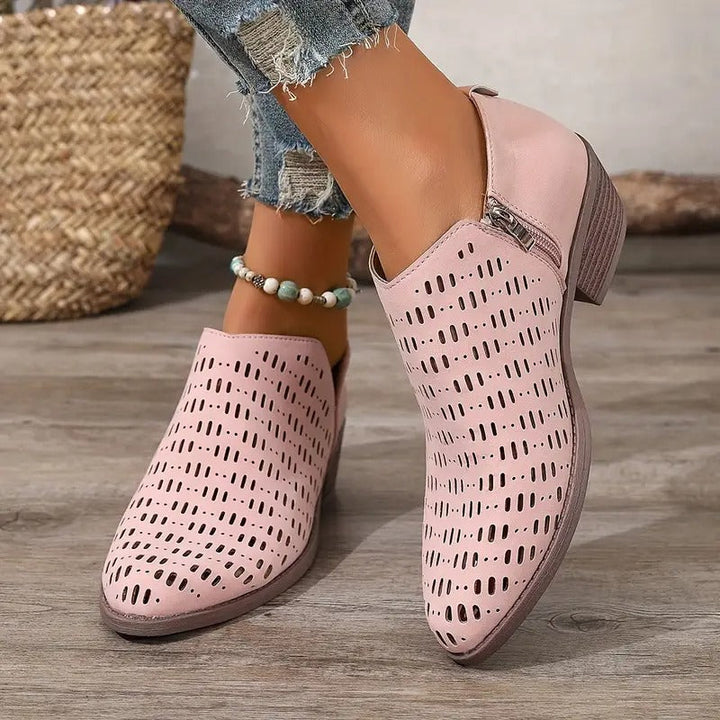 Detaljbild av luftiga ankelboots i syntetmaterial, med fokus på de unika utskärningarna, dammode.