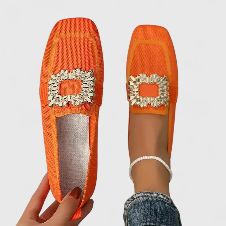 Eleganta cremevita slip-on loafers för dam, med låg klack och dekorativ utsmyckning.