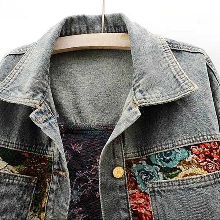 Närbild på handmålade blomsterdetaljer på en blommig jeansjacka, damjacka i denim