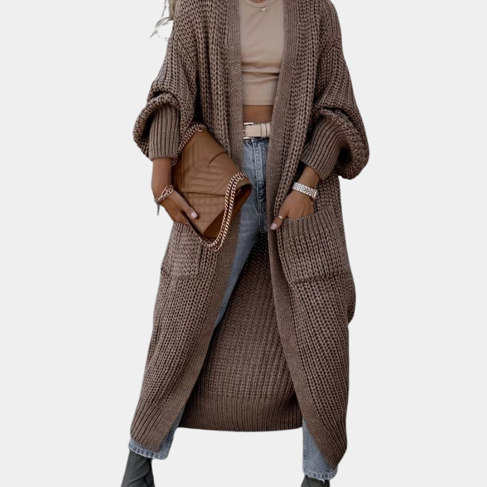 Modell bär en kvinnors långa stickade jacka, bekväm för vardagsbruk, kompletterar höstens look.