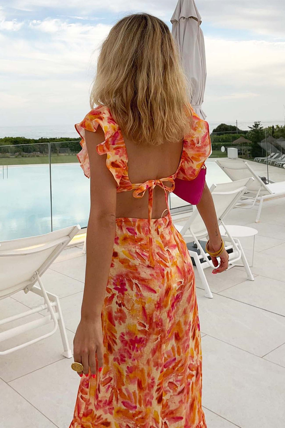 Sommarklänning: Lång orange maxiklänning med livfulla blå blommor och feminina volanger för kvinnor.