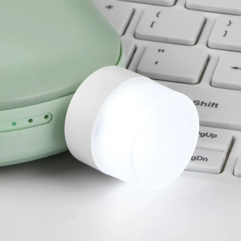 Liten USB LED nattlampa med ögonskydd, kompakt och stilren, avger mjukt vitt ljus, perfekt för sovrum och resor.
