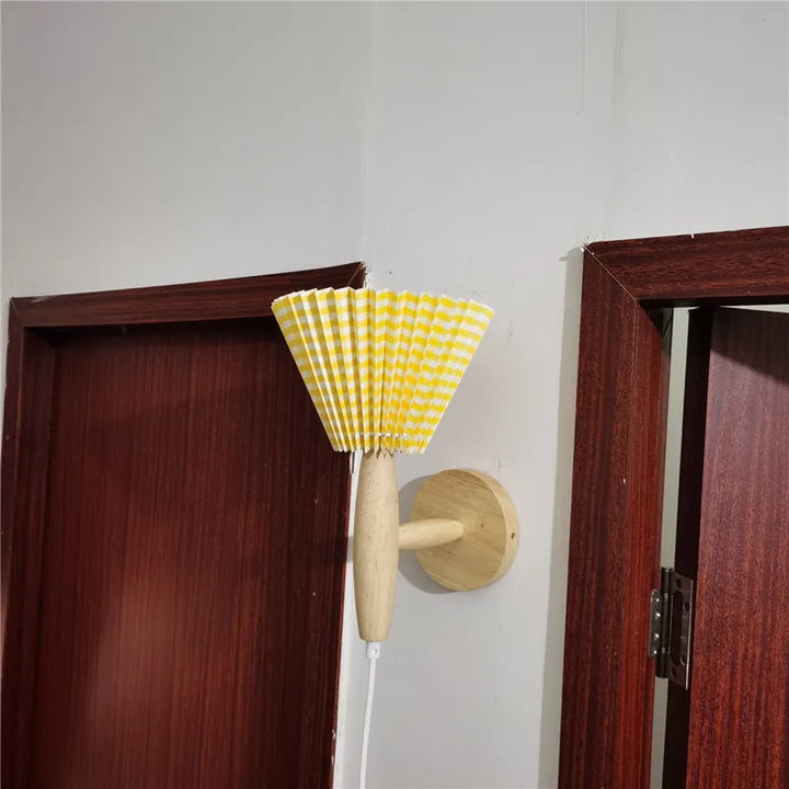 Elegant nordisk vägglampa Lyren i naturligt trä med plisserad skärm, perfekt för designmedvetna hem.