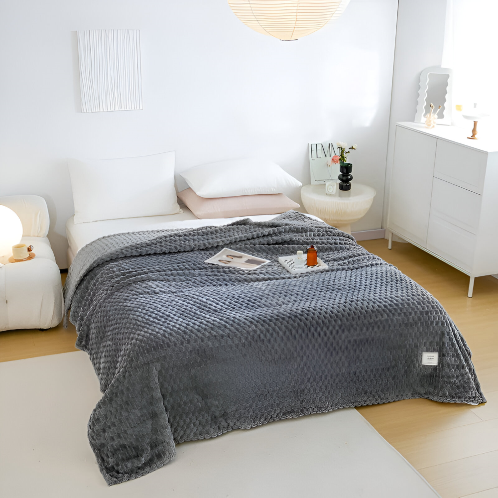 Tjock fleecefilt i grå nyans, mysig sofffilt för avkoppling, hemtextil för inredning.