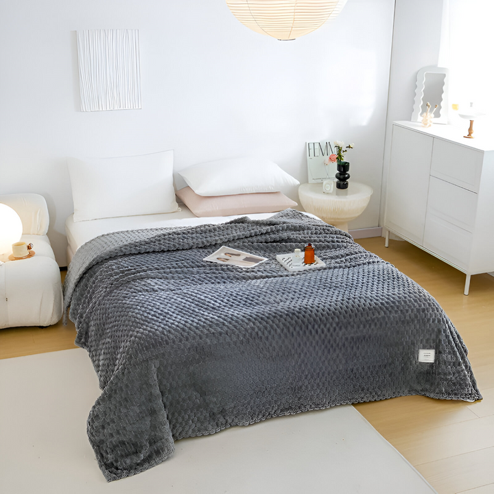 Tjock fleecefilt i grå nyans, mysig sofffilt för avkoppling, hemtextil för inredning.