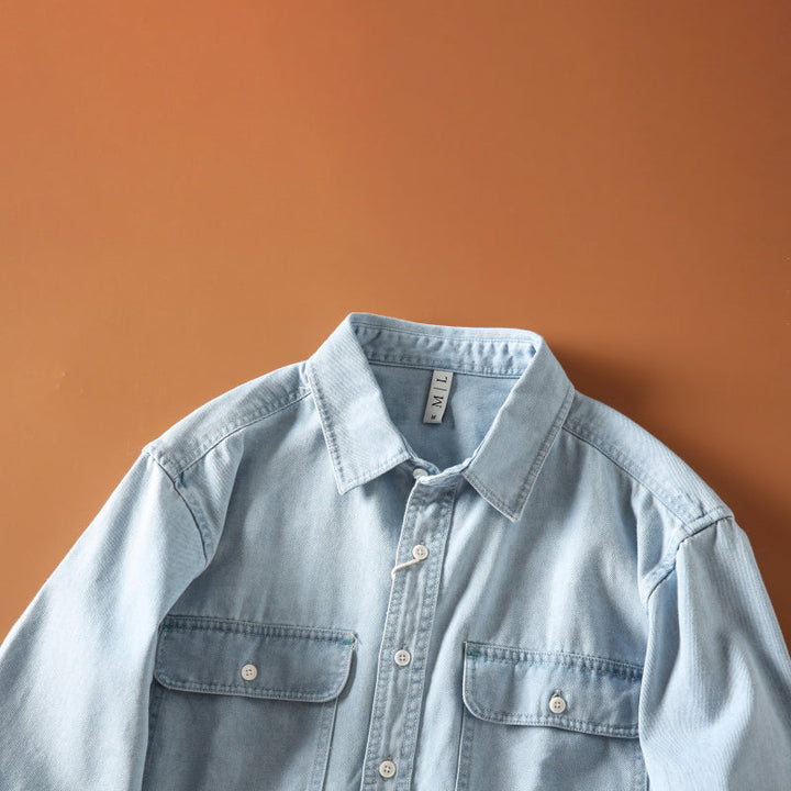 Detaljbild av tyget på en herr denimskjorta i retrostil, visar textur, vintage blå jeansskjorta för avslappnad komfort.