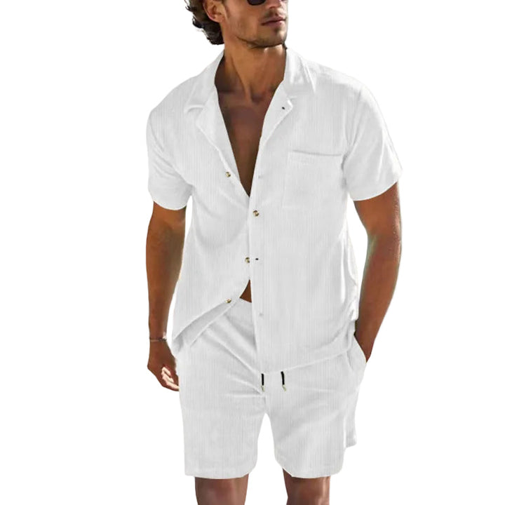 Man i snyggt avslappnat sommarset: mörkblå kortärmad skjorta med vita mönster och matchande shorts.