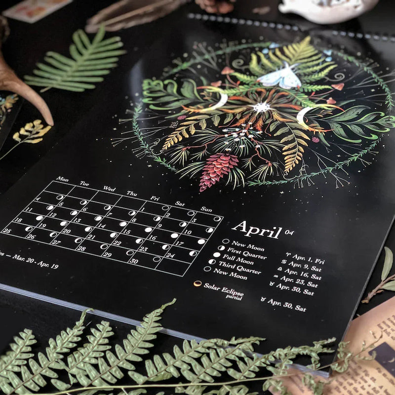 "Månkalender 2023 med mörka skogsmotiv, intrikata illustrationer, fångar natur och magi, fullmåne och stjärntecken."