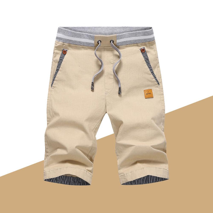 "Mäns casual shorts med elastisk midja i bomull, randig fickdetalj och bakfickor, visad framifrån i ljusgrå nyans."