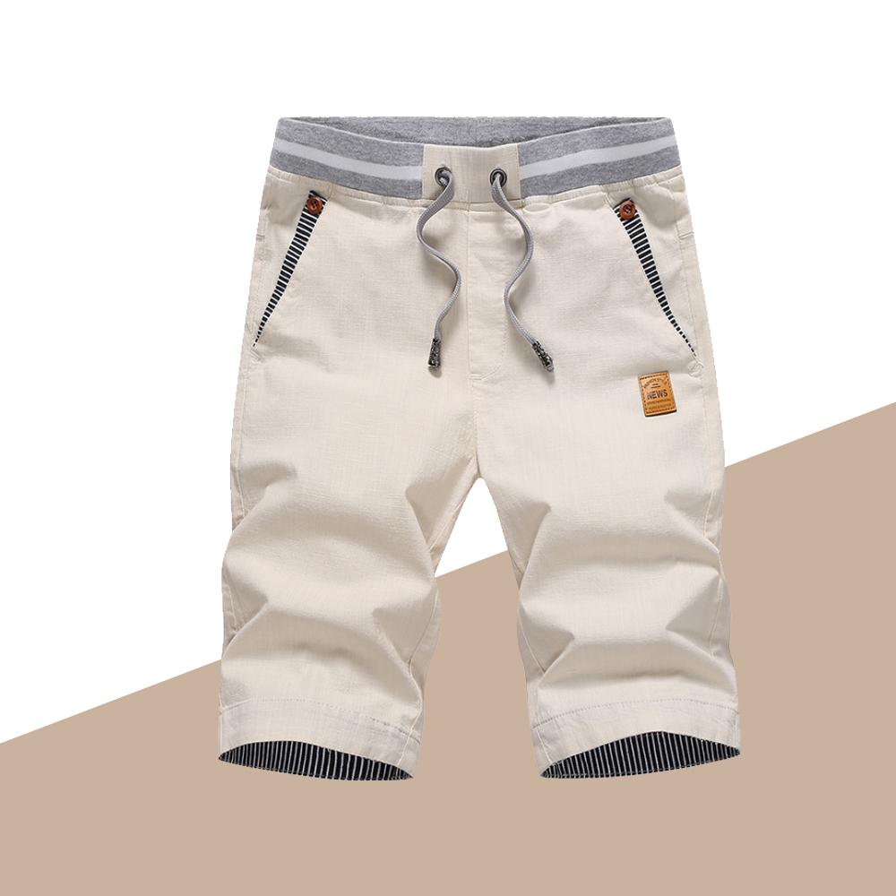 "Mäns casual shorts med elastisk midja i bomull, randig fickdetalj och bakfickor, visad framifrån i ljusgrå nyans."