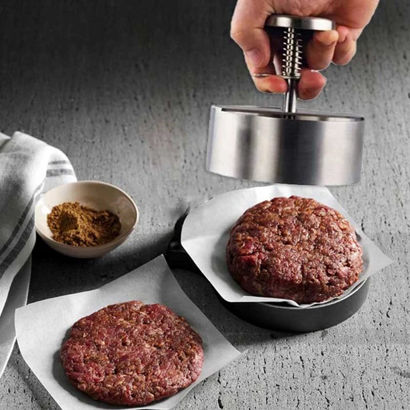 "Manuell köttpress i rostfritt stål, silverfärgad, ergonomisk design för perfekta hamburgerplättar, köksredskap."