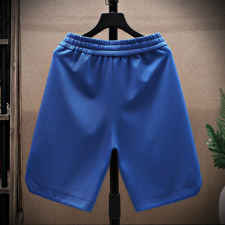 Modell bär blå herrshorts med fickor i somrig miljö, utstrålar bekväm elegans.