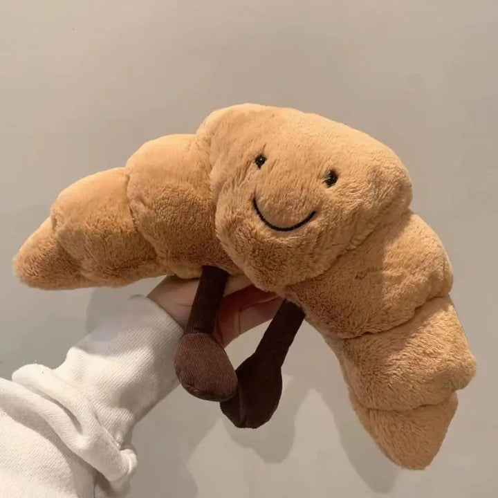Mjuk, skrattande croissant kramkudde i plysch, perfekt för barnrummet och mysiga stunder.