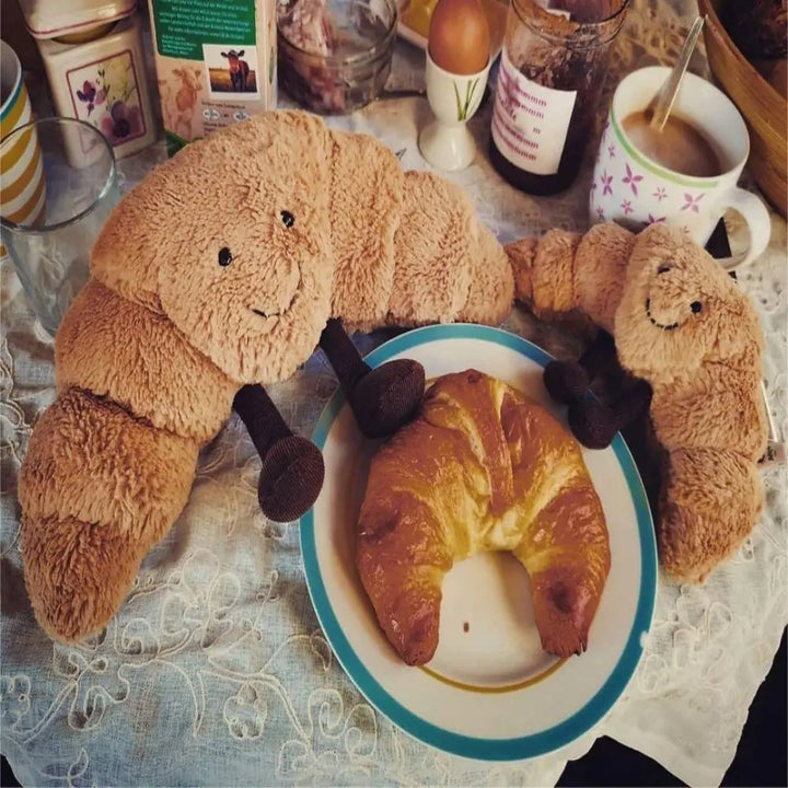 Detaljbild på den skrattande croissantens ansikte, mjukt plyschdjur och mysig kramkudde för barn.