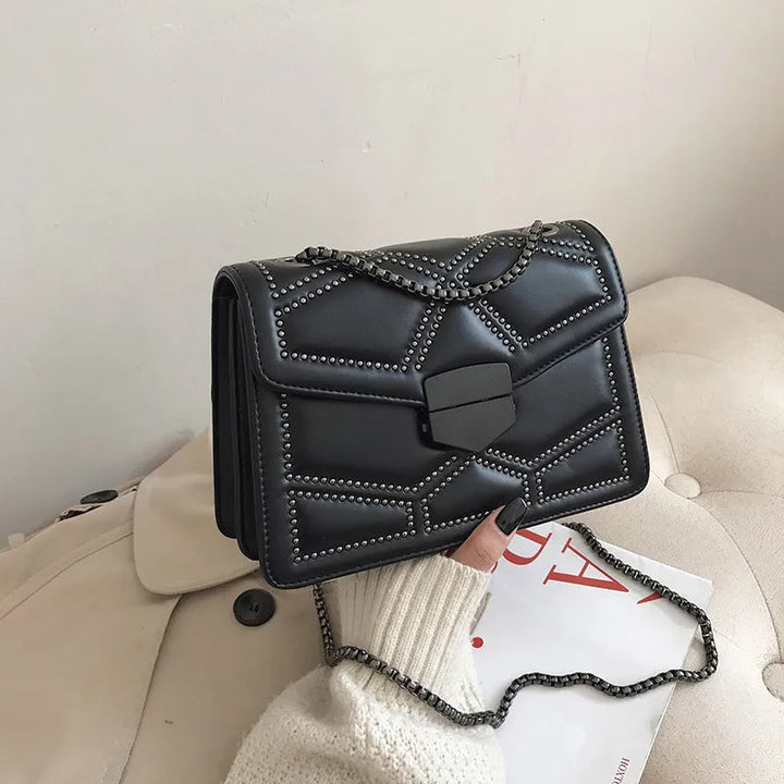Stilren crossbodyväska med glänsande nitar och axelkedja, en trendig accessoar.