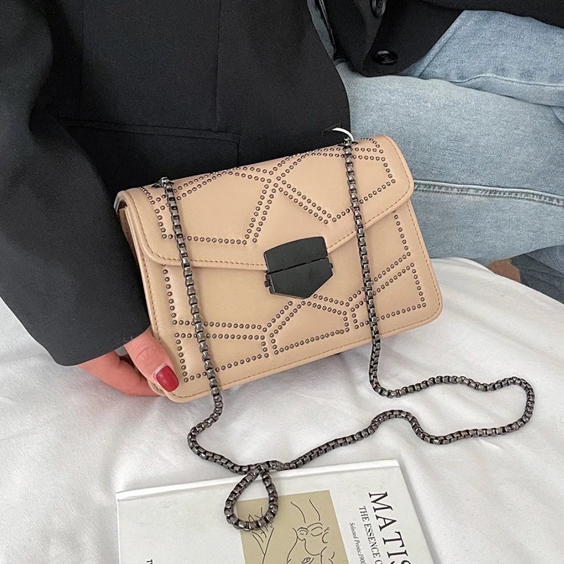 Damaxelremsväska i klassisk stil med nitdekoration och metallkedja. Mångsidig accessoar.