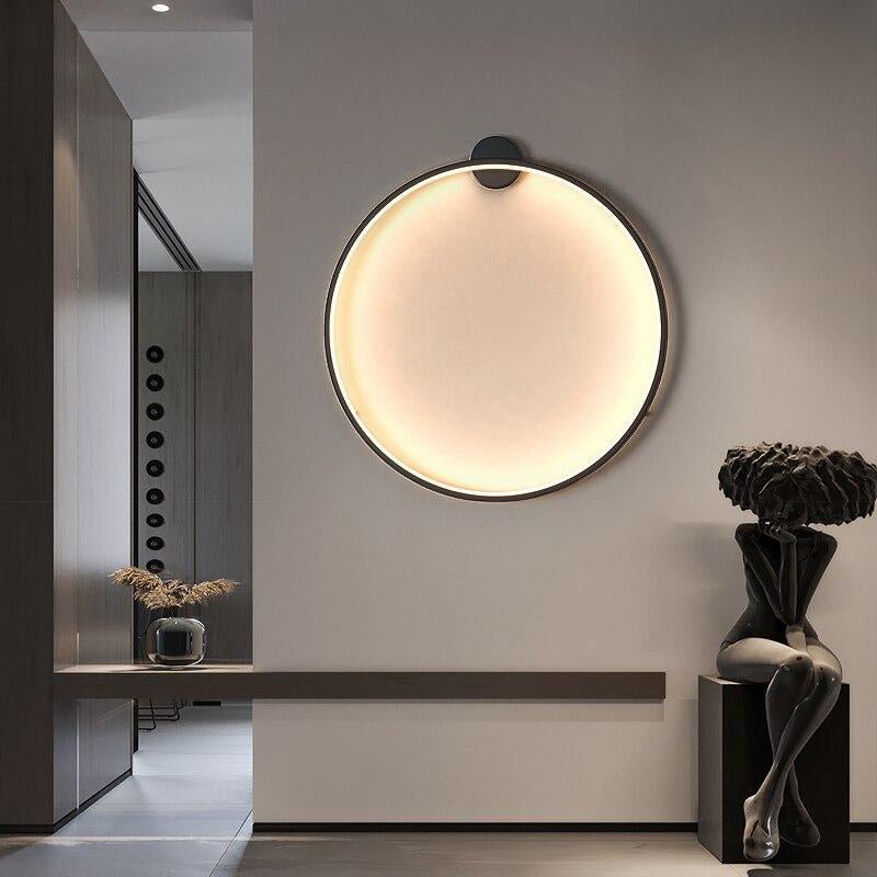 Minimalistisk LED-vägglampa, rund och svart, en stilren inredningsdetalj.