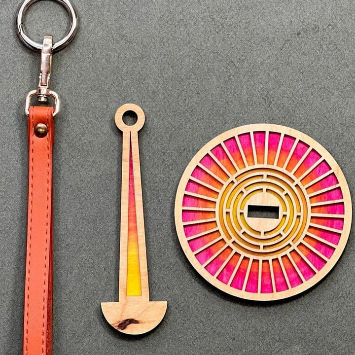 "Modern trähållare för garn i minimalistisk design, visar flera garnrullar i olika färger på en stabil träbas."