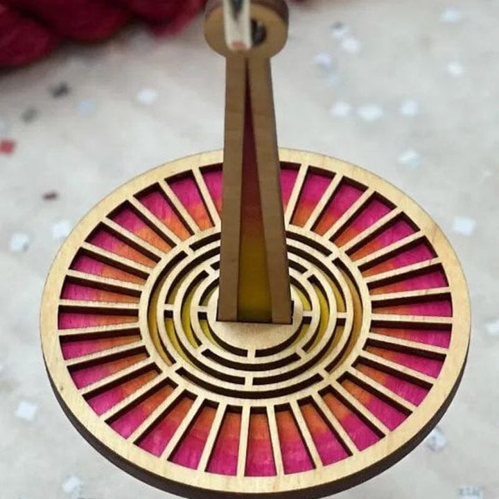 "Modern trähållare för garn i minimalistisk design, visar flera garnrullar i olika färger på en stabil träbas."